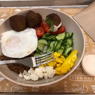 Egyptian breakfast. Fava bean stew with egg, falafel, veggies, feta with dressing on the side.