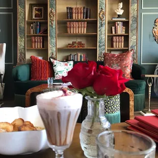a living room with a table, chairs, and bookshelves