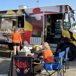 two women sitting at a table in front of a food truck
