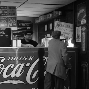 a black and white photo of a man ordering a drink