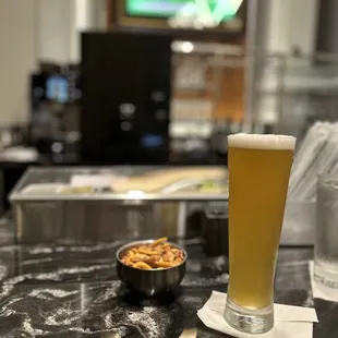 a glass of beer and a bowl of nuts