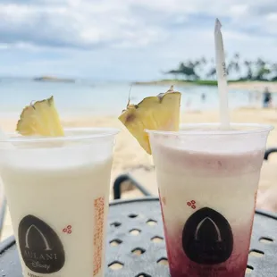 two drinks on a table on the beach