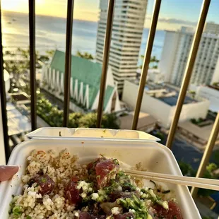 Enjoying Off the Hook Poke bowl with beautiful view of Waikiki beach during sunset