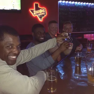 a group of men toasting at a bar