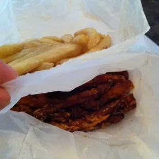 a hand holding a sandwich wrapped in paper