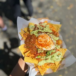 a person holding a plate of nachos