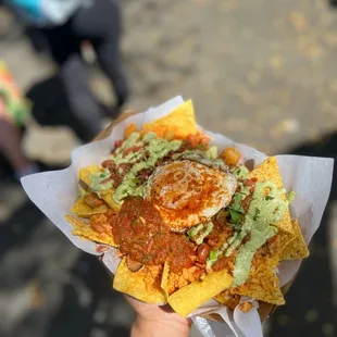a person holding a plate of nachos