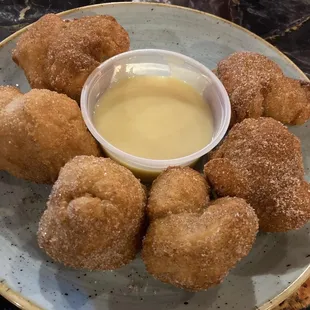 a plate of doughnuts with dipping sauce