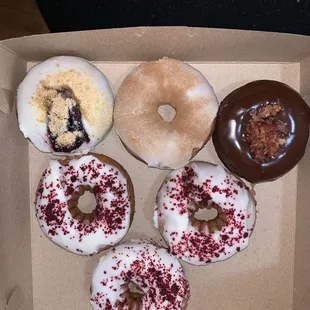 $9.95 half 1/2 Dozen Assorted Donuts top left Brown Butter Blueberry, churro and chocolate bacon, then three red velvet.
