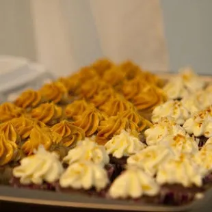 a tray of cupcakes with white frosting