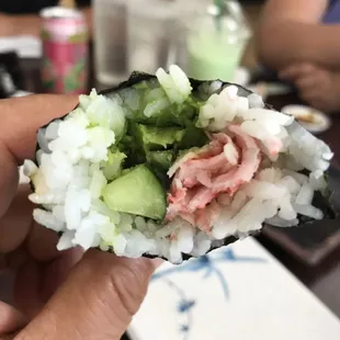 a hand holding a piece of sushi