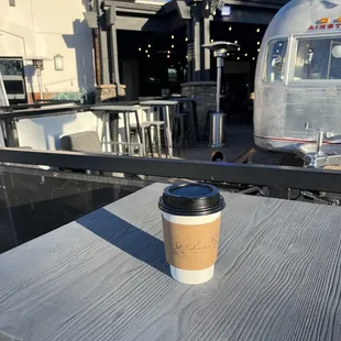 a coffee cup on a table with a airstream in the background