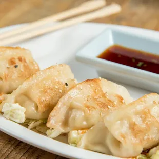 a plate of dumplings with a dipping sauce