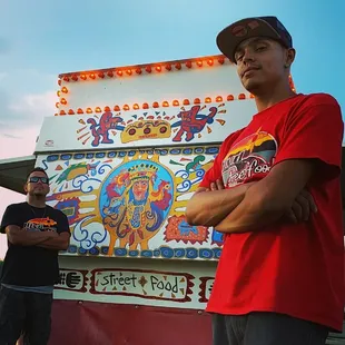 two men standing in front of a food truck