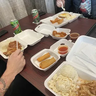 Mini platers with a scoop of rice, macaroni salad, and entree, small boxes of lumpia and chicken katsu