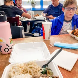 a young boy sitting at a table with a plate of food in front of him