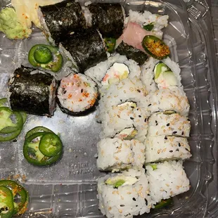 a plastic container with sushi and jalapenos