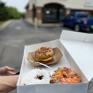a person holding a box of donuts
