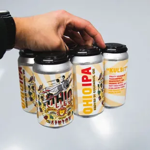 a hand holding three cans of beer