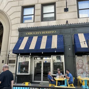 people sitting at tables outside a restaurant