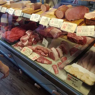 a dog looking at meat in a display case