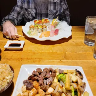 a man sitting at a table with a plate of sushi