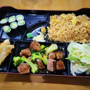 Dinner box with teriyaki steak, fried rice, fried dumplings, and an avacado roll