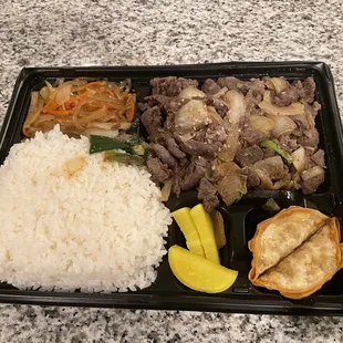 a tray of rice, meat, and vegetables