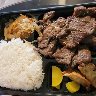 a bento lunch with rice, meat and vegetables