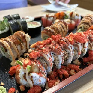 Assortment of sushi. Up front is Fuego Roll (hot Cheetos on top). Mean Jada (back left), Cherry Blossom (back right). Red Dragon (middle)