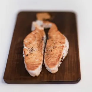 two pieces of salmon on a cutting board