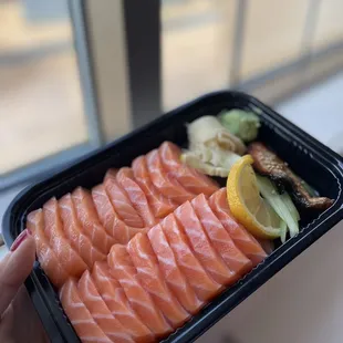 a person holding a tray of salmon