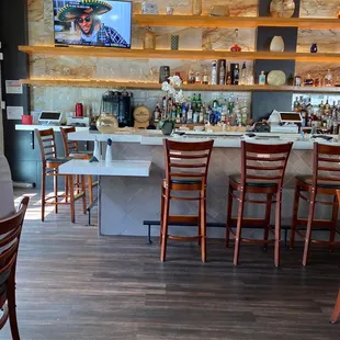 a bar with wooden chairs and a flat screen tv