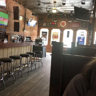 a bar with stools and televisions
