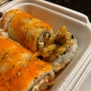 two rolls of sushi in a styrofoam container