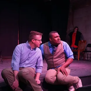 two men sitting on a stage