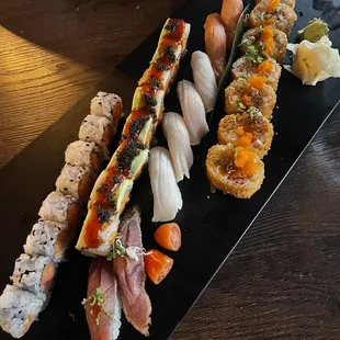 various types of sushi on a black plate