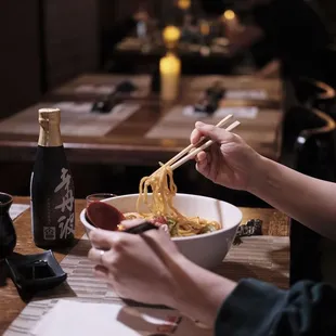 a woman eating noodles with chopsticks