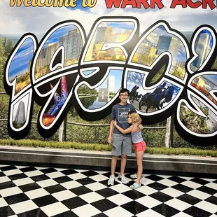 two children standing in front of a mural