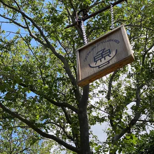 a wooden sign hanging from a tree
