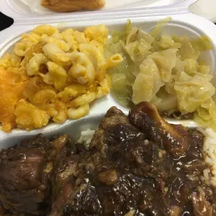 Oxtails over rice with macaroni and cheese, cabbage, and dinner roll.