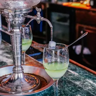 a glass of green liquid with a spoon in it