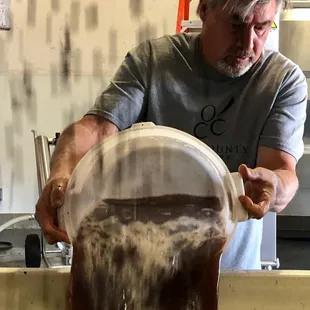 a man pouring wine into a bucket