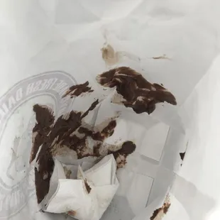 a dirty donut in a paper bag