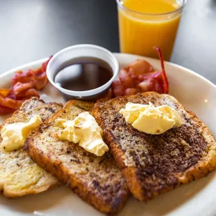 a plate of french toast with butter and bacon