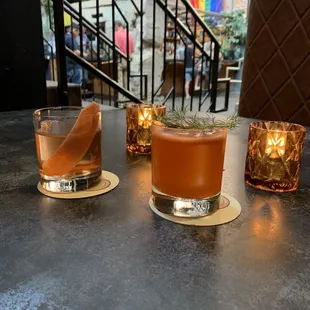 two glasses of old fashioned cocktails on a table