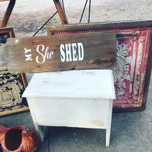 Stenciled sign, framed ceiling tile, small bench with storage, chicken planter
