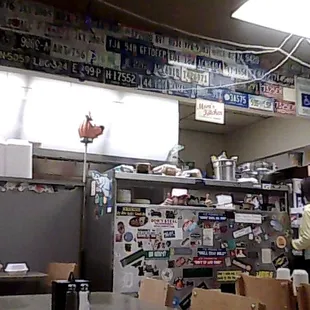 A collection of license plates above and customer&apos;s bumper stickers near the cook&apos;s station.