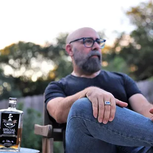 a man sitting in a chair with a glass of whiskey