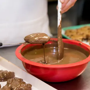 a person dipping chocolate into a bowl
